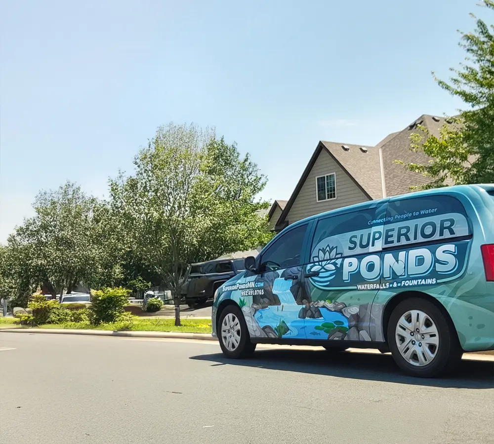 Superior Ponds branded van parked beside sign showcasing professional pond and waterfall installation services.